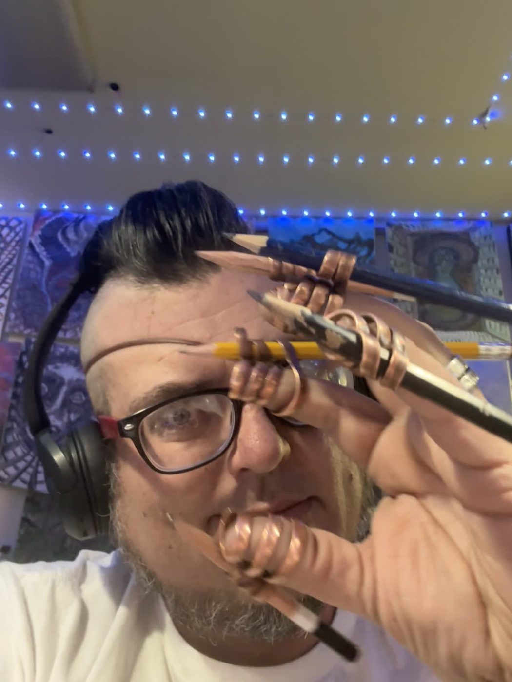 Jesse Montero, headphones on, copper pencil rigs on both hands, looking at the camera